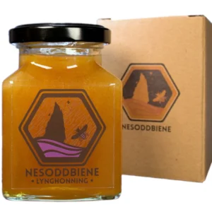Image showing our ling heather honey in a square jar. In the background you can see the carboard box used to protect the jar during shipping.